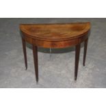 A George III mahogany folding games table Having a demi lune and cross banded folding top