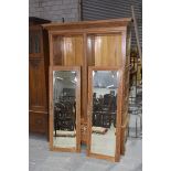 A late Victorian satinwood wardrobe Having an over hanging pediment above a pair of mirrored doors