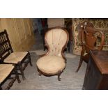 A Victorian balloon back walnut framed nursing chair Having a leafy carved crest above a circular