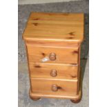 A modern pine beside chest Three drawers each applied with hardwood knob handles, raised upon bun