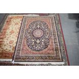 The foliate and arabesque style carpet In shades of red, blue and beige upon red ground, 230 x