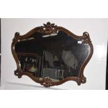 A French Rococo style wall mirror The simulated wood stained surround of scroll form detailed with