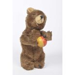 A brown plush clockwork bear holding yellow and red ball Probably Schuco, height 19cm