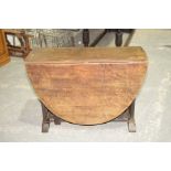 A 19th Century oval oak drop leaf dining table The oval top supported on substantial trestle type