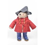 A light brown plush Paddington Bear With glass button eyes, in dark grey hat, red dufflecoat and