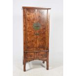 A Chinese stained elm cabinet The twin doors fitted with a brass bar lock enclosing two fixed
