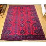 A large 20th Century wool floor rug Decorated with a central panel of stylised motifs, surrounded by