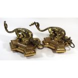 A pair of gilt metal gargoyles Each with arched backs holding a ring in their mouths, raised on gilt