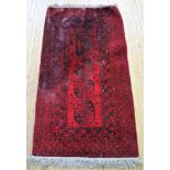 A 20th Century Bokhara type wool floor rug Decorated with a central geometric panel on a red