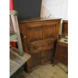 A good quality Priory style solid oak cocktail cabinet of triangular form, having pull-down cupboard