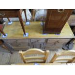 A Victorian pine dresser base with a central cupboard door and an arrangement of seven drawers