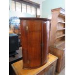 A George III oak and mahogany crossbanded bowfront hanging corner cupboard