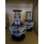 A pair of contemporary Chinese blue and white cloisonne vases with accompanying wooden stands.