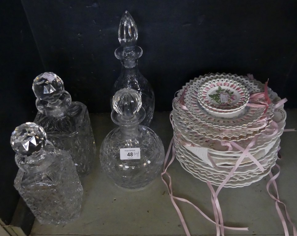 A collection of assorted ribbon plates and four various clear glass decanters.