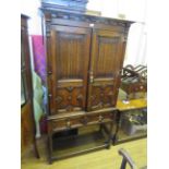 A 1920s oak Jacobean revival chest on stand, the doors with linen fold panels enclosing an