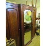 A large Victorian mahogany breakfront wardrobe with central mirrored door and two panelled side