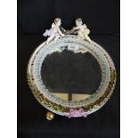 A 19th Century German porcelain dressing table mirror Decorated in relief with two cherubs holding a