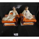 A pair of Staffordshire models formed as figures on chaise lounge.
