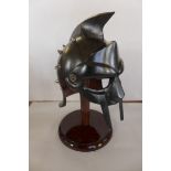 A Gladiator 'General Maximus' helmet on stand, the metal helmet with stud decoration, raised on