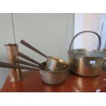 A 19th Century brass skillet with a swing handle, four graduated brass saucepans and a brass shell.