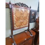 A Victorian walnut glazed needlework fire screen on barley twist supports