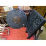 An Indian ebonised carved hardwood and brass inlaid circular table on folding octagonal stand