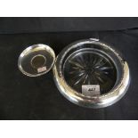 A cut clear glass ashtray of circular form fitted with a silver mount together with a further