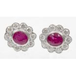 A pair of ruby and diamond cluster earrings Each designed as an oval shaped ruby within a