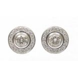 A pair of diamond halo earrings Each designed as a brilliant cut diamond collet within a similarly