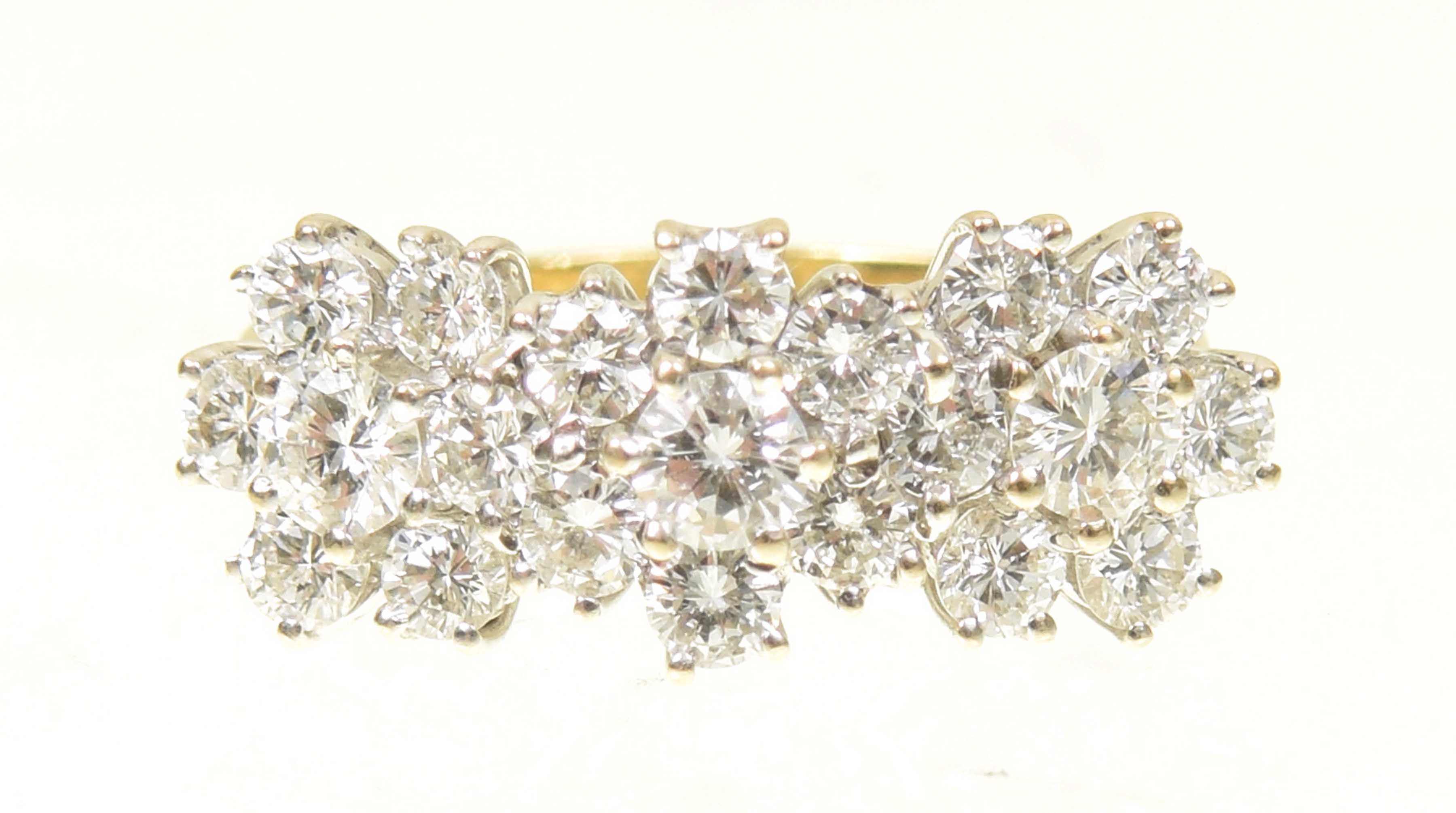 An 18ct gold diamond cluster ring Designed as a trio of brilliant cut diamond floral clusters,