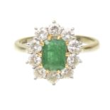 An emerald and diamond cluster ring The rectangular shaped emerald within a brilliant cut diamond
