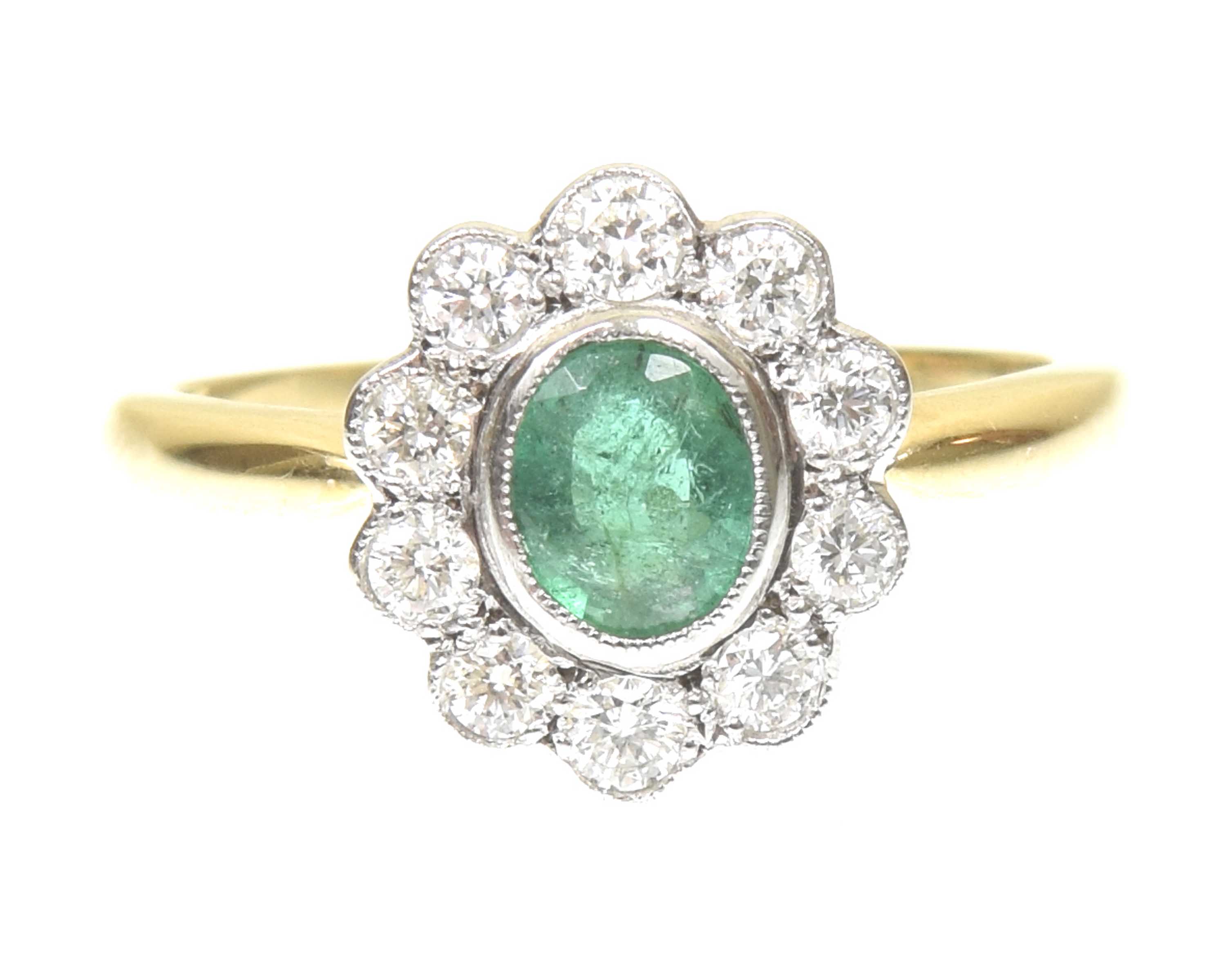 An emerald and diamond cluster ring The oval shape emerald within a brilliant cut diamond