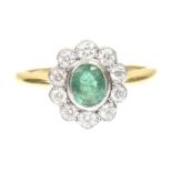 An emerald and diamond cluster ring The oval shape emerald within a brilliant cut diamond