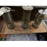 Three assorted brass miners lamp To include an example by E Thomas and Williams and two others.