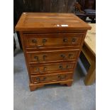 A reproduction yew wood chest of drawers, of small proportions.