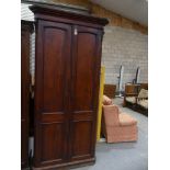 A 19th Century mahogany hall cupboard Having a moulded cornice above canted corners enclosing two