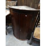 A George III oak and mahogany crossbanded bowfront hanging corner cupboard.