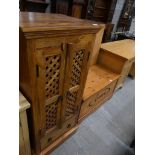 A Contemporary hardwood cabinet with a pair of lattice open work doors above a single drawer.