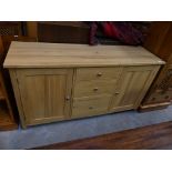 A Contemporary light oak sideboard with 3 central drawers flanked by cupboard doors.