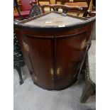 A George III oak and mahogany crossbanded bowfront hanging corner cupboard.