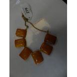 An amber style necklace The rectangular amber style panels with orange bead spacers and yellow metal