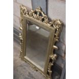 An ornate carved giltwood beveled wall mirror.
