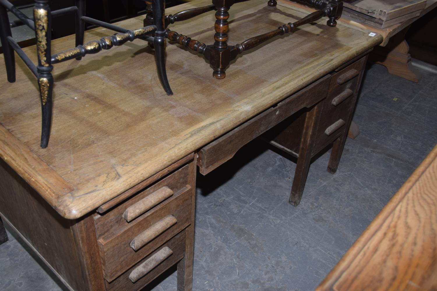 A 20th Century oak desk with an arrangement of seven drawers.