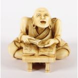 NETSUKE RAKAN MAUDGALYAYANA, Elfenbein, sehr seltenes Motiv, hinter einem niedrigen Tisch sitzend,