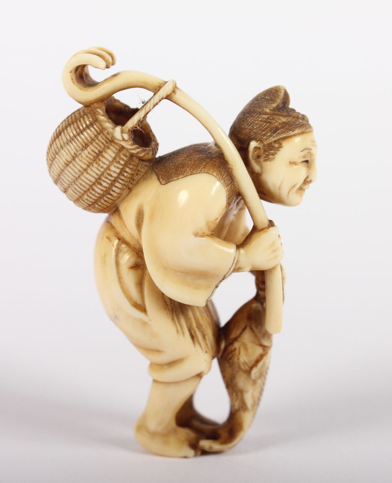 NETSUKE FISCHER, Elfenbein, der Mann mit Binsenschurz und spitzer Mütze hält in der Rechten einen - Bild 2 aus 5