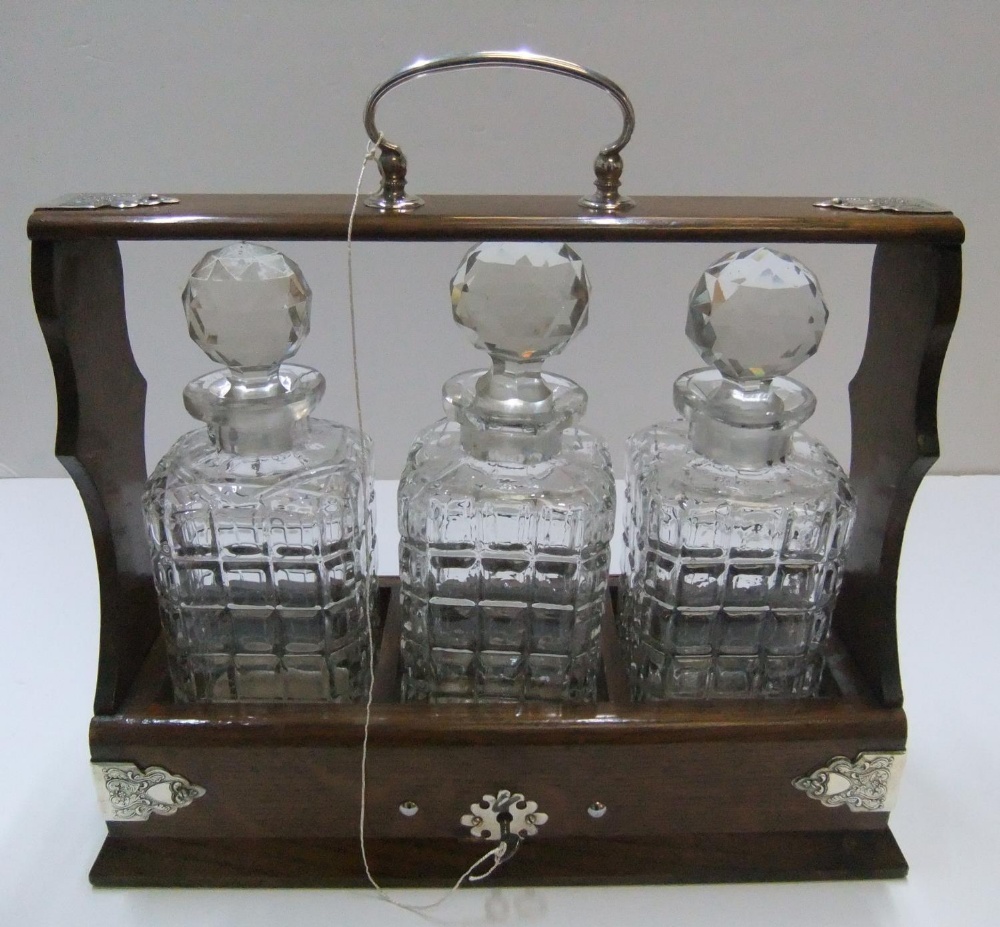 3 bottle Edwardian Tantalus, with key 35 cm long The bottles all have small chips to the neck, the