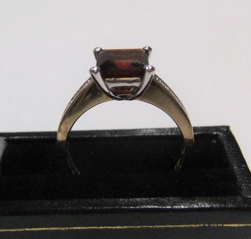 9ct gold ring with a princess cut garnet and with diamonds on each shoulder Approx 3.6 grams