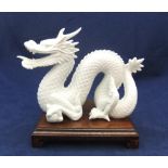Finely detailed, white fired ceramic dragon (unmarked) on chinese wood plinth, 21 cm long