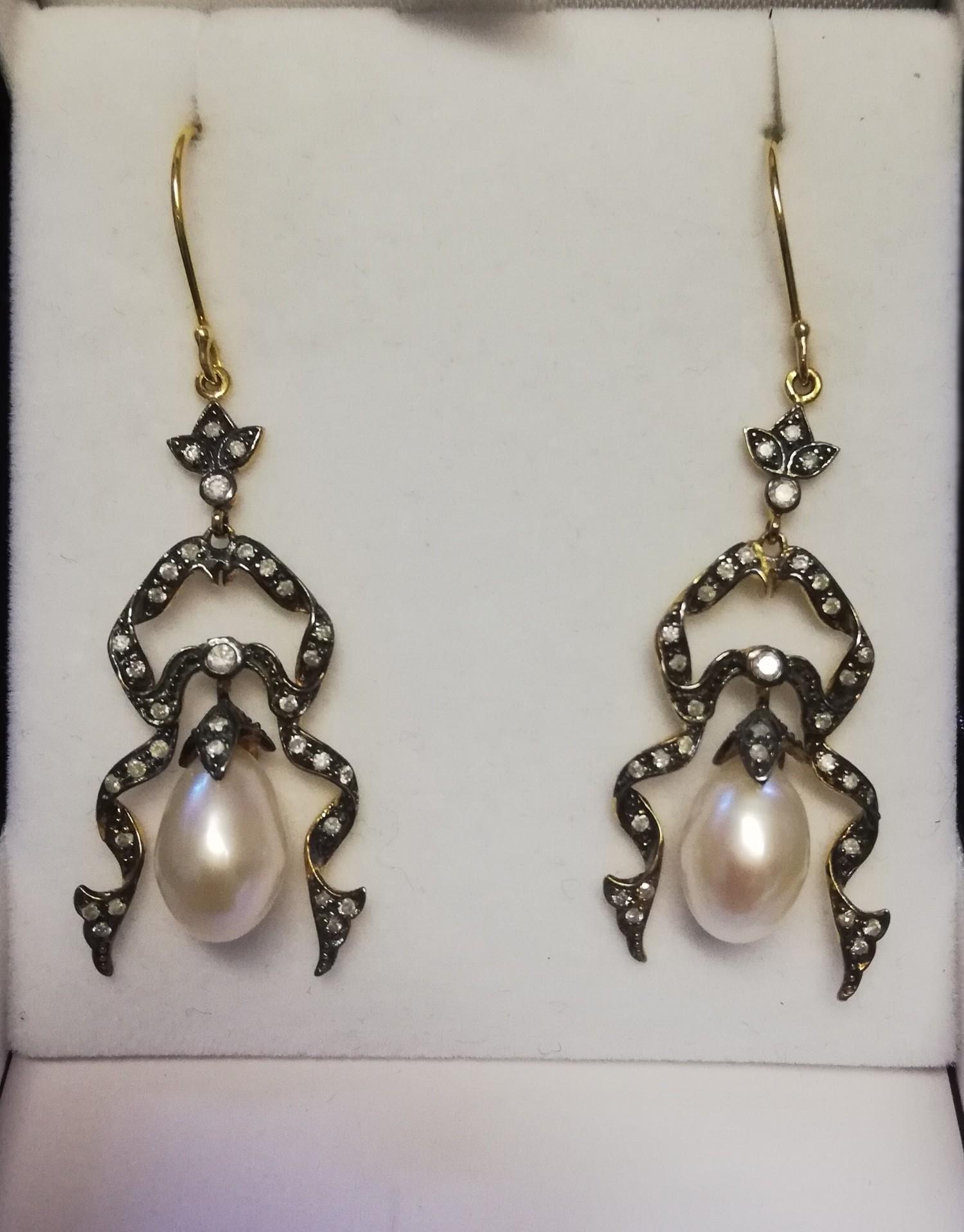 Pair of ornate drop earrings set with diamonds and a suspended pearl