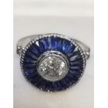 Large platinum target style ring set with central diamond and calibre cut sapphires